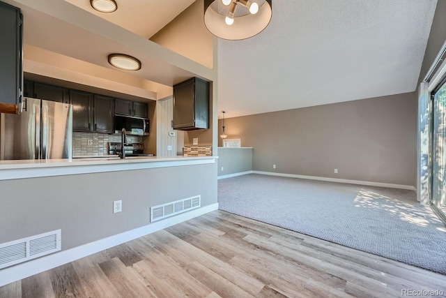 kitchen with visible vents, baseboards, appliances with stainless steel finishes, and vaulted ceiling