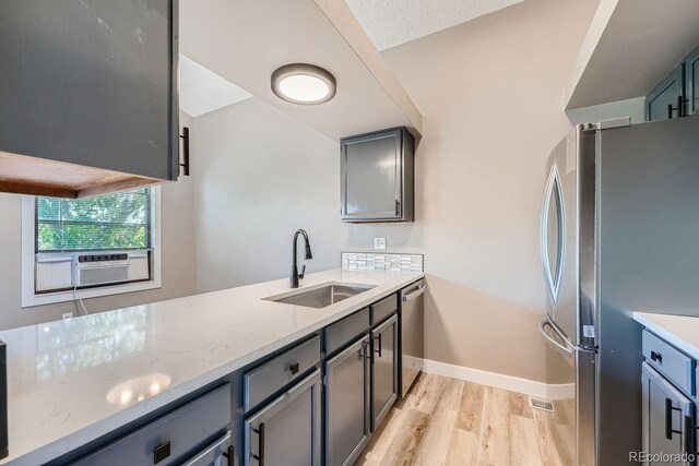 kitchen featuring light wood-style flooring, a sink, light stone counters, cooling unit, and appliances with stainless steel finishes