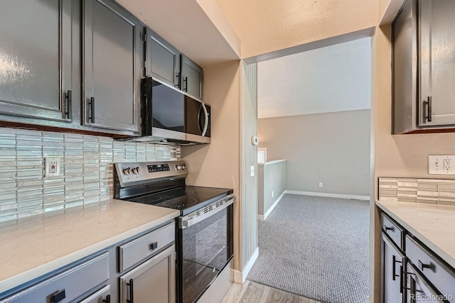 kitchen featuring gray cabinets, tasteful backsplash, appliances with stainless steel finishes, baseboards, and light stone countertops