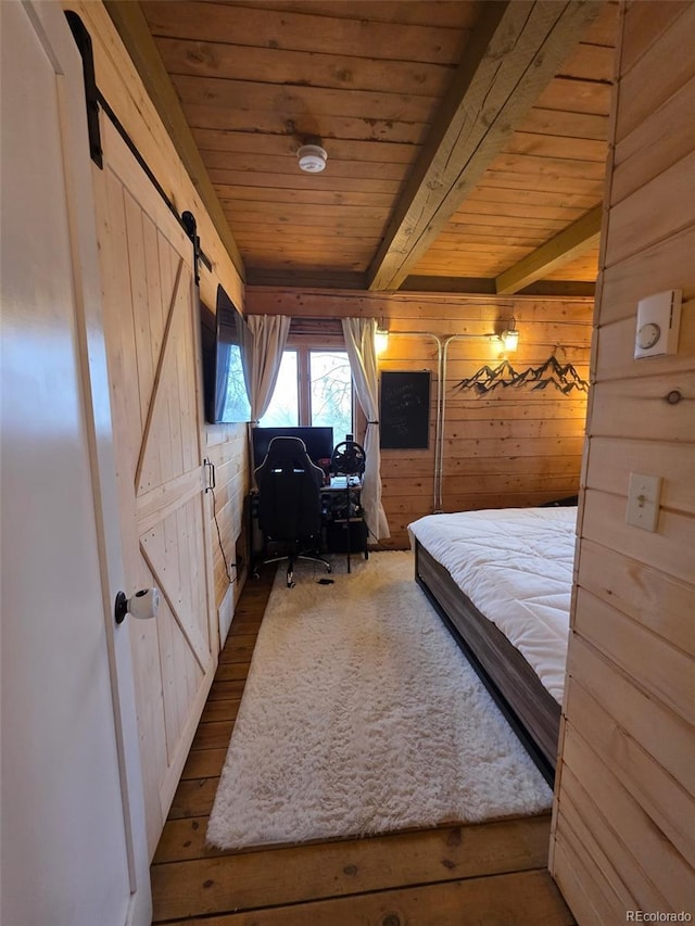 253 Bear Ln, Jefferson, CO 80456 - bedroom with a barn door, wood walls, a wooden ceiling with exposed beams, wood finished floors, and a desk