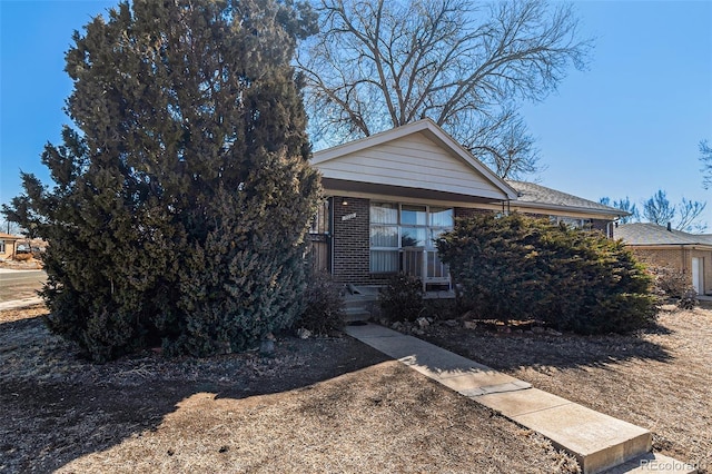 obstructed view of property featuring covered porch and brick siding