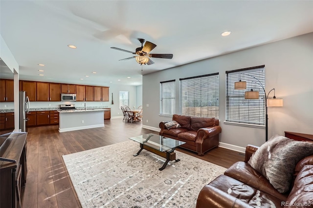 living room with dark wood-type flooring, ceiling fan, and sink