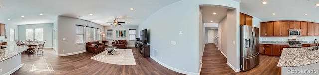 kitchen with light stone countertops, appliances with stainless steel finishes, ceiling fan, and dark hardwood / wood-style flooring