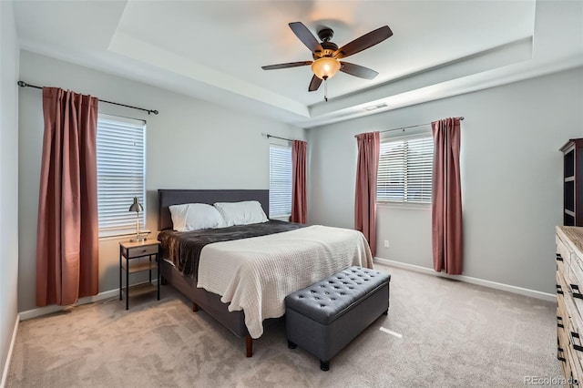 carpeted bedroom featuring a raised ceiling and ceiling fan