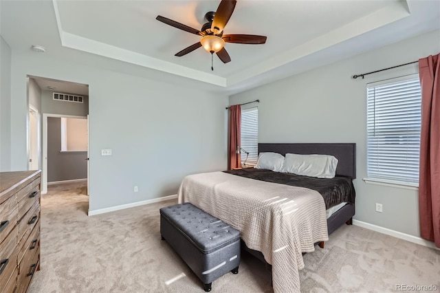 carpeted bedroom featuring ceiling fan and a tray ceiling