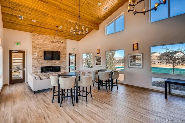 dining space with light wood-type flooring, wooden ceiling, a chandelier, and a fireplace