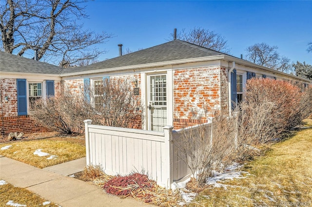 view of home's exterior featuring a shingled roof and brick siding