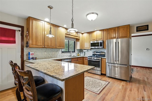 2140 S Youngfield St, Lakewood, CO 80228 - kitchen with a peninsula, light stone countertops, tasteful backsplash, a sink, and appliances with stainless steel finishes