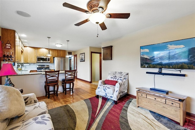2140 S Youngfield St, Lakewood, CO 80228 - living room featuring baseboards, a ceiling fan, and light wood-style flooring