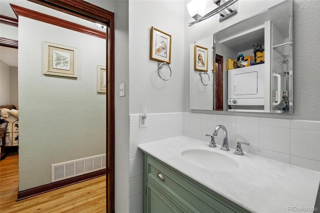 2140 S Youngfield St, Lakewood, CO 80228 - bathroom with visible vents, tile walls, stacked washer / drying machine, wood finished floors, and vanity
