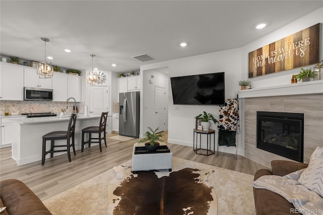 8132 Mt Harvard Rd, Littleton, CO 80125 - living area with light wood finished floors, recessed lighting, a fireplace, a chandelier, and baseboards