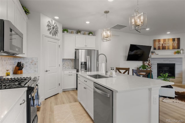 8132 Mt Harvard Rd, Littleton, CO 80125 - kitchen featuring stainless steel appliances, a sink, open floor plan, light wood-type flooring, and a chandelier
