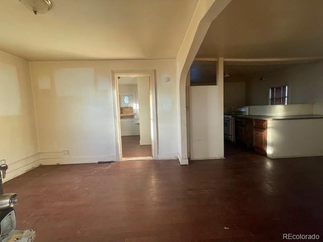 2771 W 1st Ave, Denver, CO 80219 - unfurnished living room with arched walkways, baseboards, and dark wood-style floors