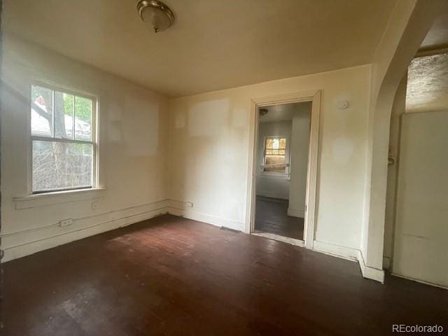 2771 W 1st Ave, Denver, CO 80219 - empty room with baseboards, arched walkways, and dark wood-style floors