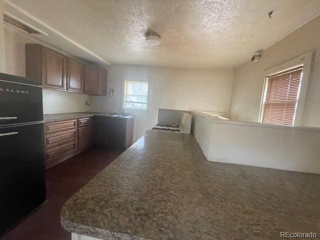 2771 W 1st Ave, Denver, CO 80219 - kitchen featuring freestanding refrigerator, a textured ceiling, and brown cabinets