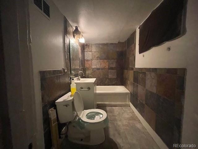 2771 W 1st Ave, Denver, CO 80219 - full bathroom with toilet, a bathing tub, a sink, tile walls, and visible vents