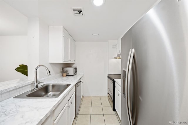 kitchen featuring white cabinets, stainless steel appliances, light tile patterned flooring, and sink