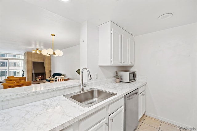 kitchen featuring sink, light tile patterned floors, decorative light fixtures, dishwasher, and white cabinetry