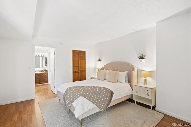 bedroom with ensuite bath, a closet, and light hardwood / wood-style flooring