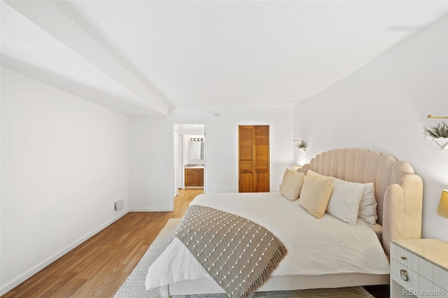 bedroom featuring ensuite bathroom and light hardwood / wood-style floors