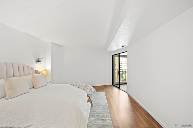 bedroom with access to exterior, light hardwood / wood-style flooring, and a textured ceiling