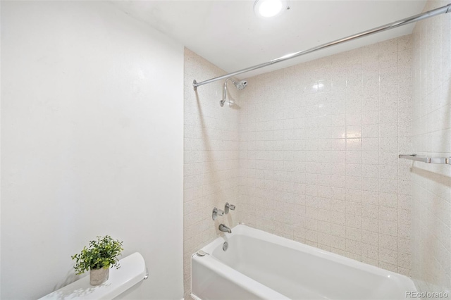 bathroom with toilet and tiled shower / bath