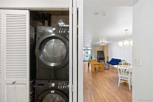 laundry area featuring a chandelier, light hardwood / wood-style floors, and stacked washer / drying machine