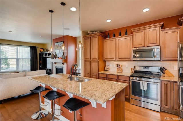 kitchen featuring stainless steel appliances, open floor plan, a sink, and light wood-style floors