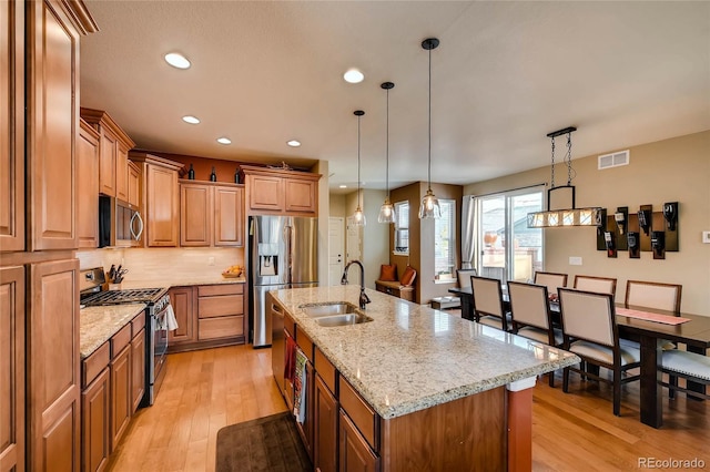 kitchen featuring light wood-style floors, visible vents, stainless steel appliances, and a sink