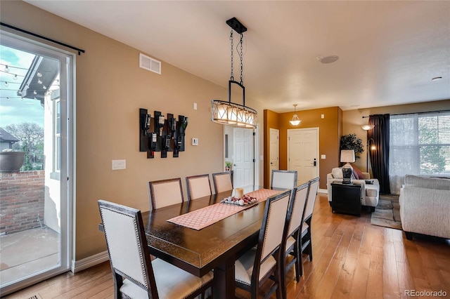dining room with baseboards, light wood-style floors, and visible vents