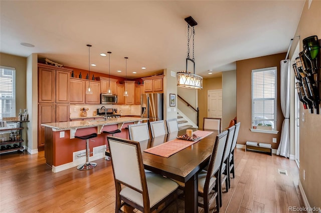 dining space with light wood-style flooring, a wealth of natural light, baseboards, recessed lighting, and stairs