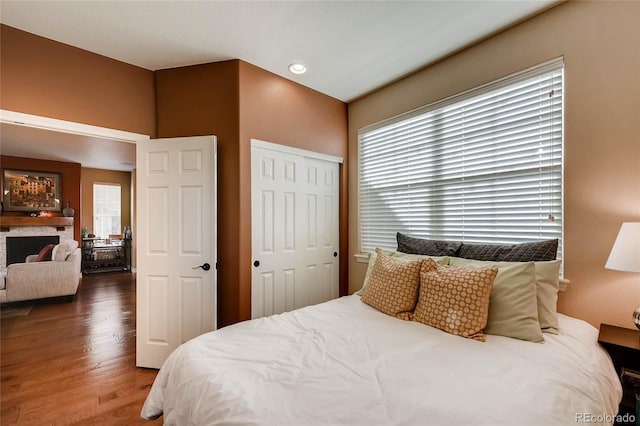 bedroom featuring a fireplace, recessed lighting, wood finished floors, and a closet