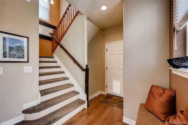 stairway with baseboards, wood finished floors, and a wealth of natural light