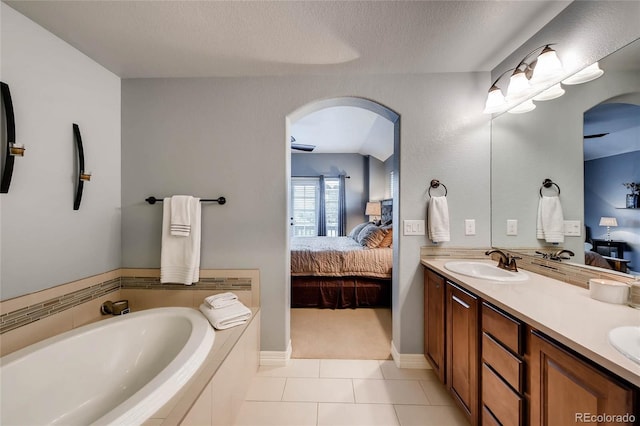 ensuite bathroom with tile patterned floors, double vanity, a sink, ensuite bath, and a garden tub