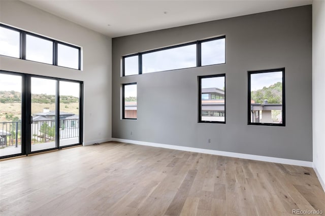 spare room with a high ceiling and light wood-type flooring