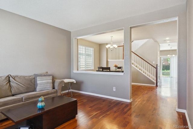 living room with a chandelier, wood finished floors, baseboards, and stairway