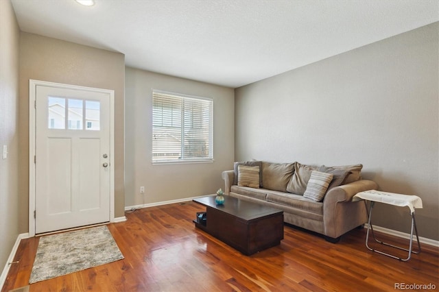 living area with dark wood-type flooring and baseboards