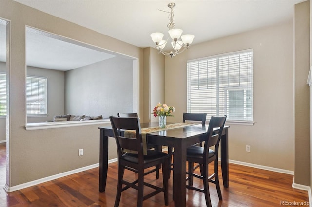 dining space with a chandelier, wood finished floors, and baseboards
