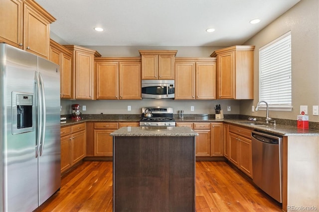kitchen featuring stainless steel appliances, a sink, dark wood finished floors, a center island, and recessed lighting