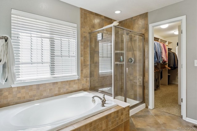 full bathroom with a stall shower, a spacious closet, a bath, tile patterned flooring, and baseboards