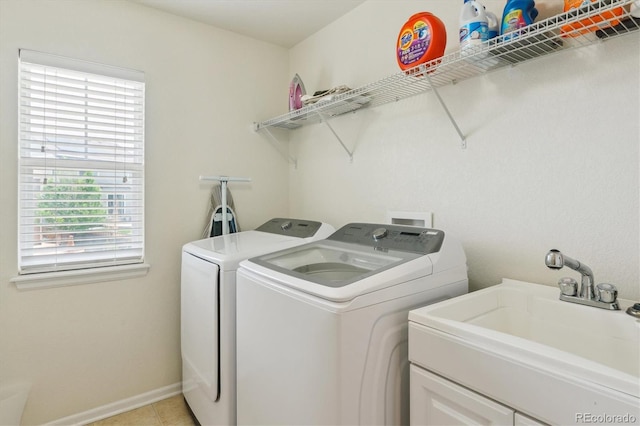 laundry area featuring washing machine and clothes dryer, light tile patterned floors, and baseboards