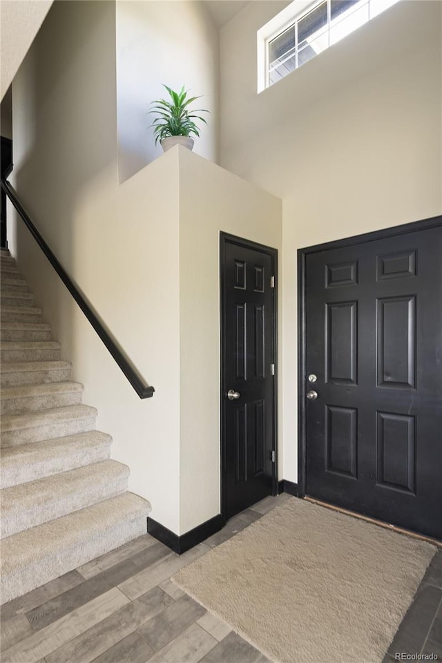 entrance foyer with a high ceiling, baseboards, stairway, and wood finished floors