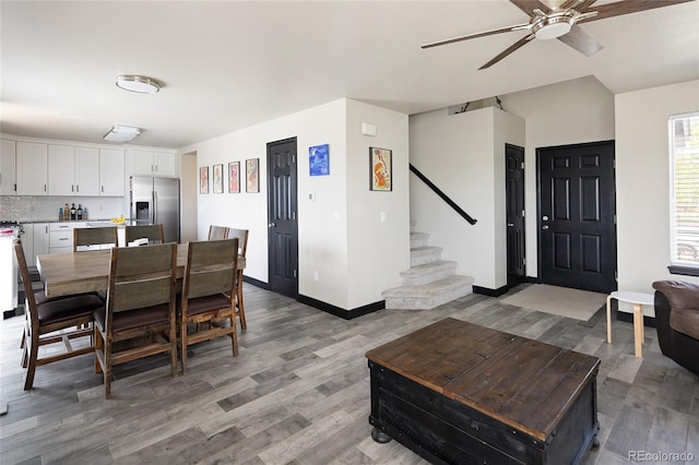 dining room featuring ceiling fan, stairs, light wood finished floors, and baseboards