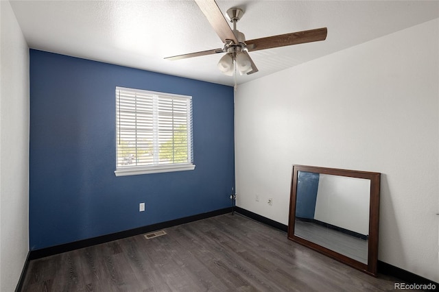 empty room with a ceiling fan, dark wood finished floors, and baseboards