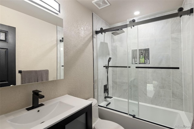 full bath featuring a textured wall, combined bath / shower with glass door, toilet, and vanity