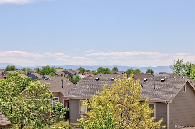 view of front facade with a residential view, a shingled roof, and a mountain view