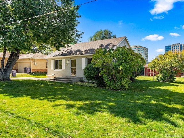 view of front of property with an outdoor structure, a garage, a shingled roof, a front lawn, and a storage unit