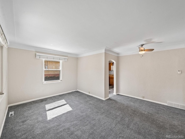 unfurnished room featuring arched walkways, a ceiling fan, visible vents, and dark carpet