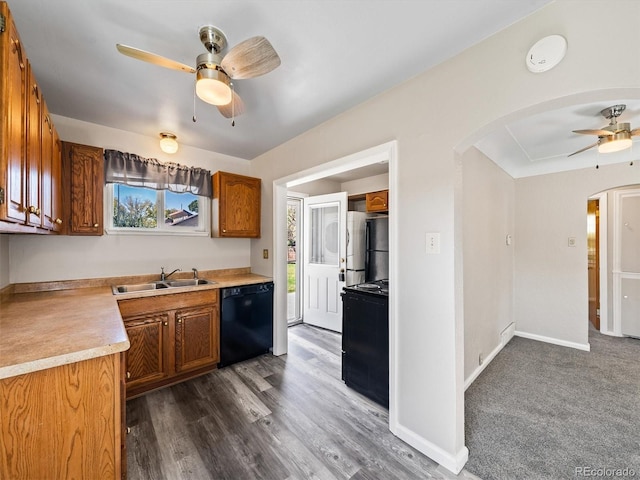 kitchen featuring a sink, brown cabinetry, ceiling fan, black appliances, and arched walkways