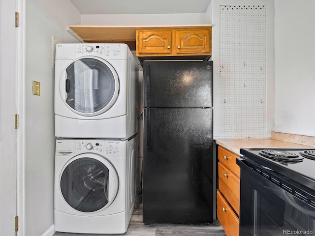 washroom featuring laundry area, wood finished floors, and stacked washer and dryer
